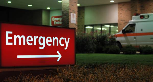 Emergency room sign with ambulance in the background.